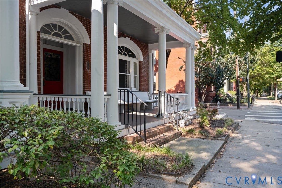 1527 Grove Avenue, #3, Richmond, VA 23220 Brick exterior with a covered porch featuring white columns, a red entry door, decorative arched windows, and wrought iron railings