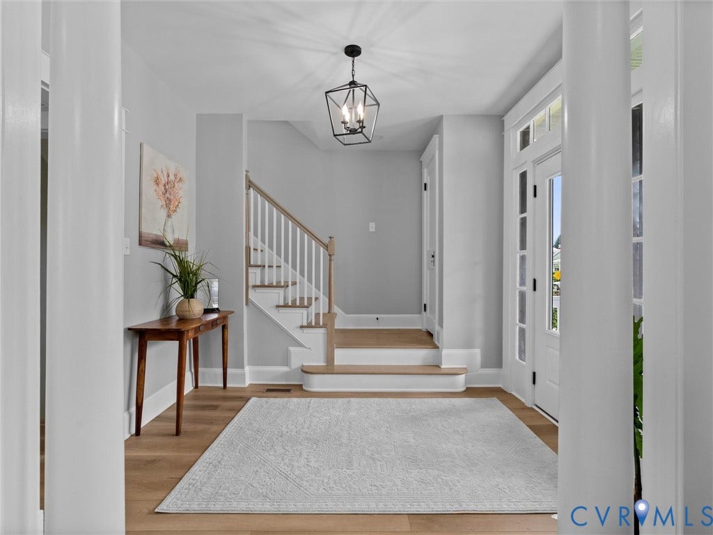 2623 Northumberland Avenue, Richmond, VA 23220 Light wood-finish flooring, staircase with white risers and wood treads, white paneled entry door with sidelights, and a black geometric pendant light fixture