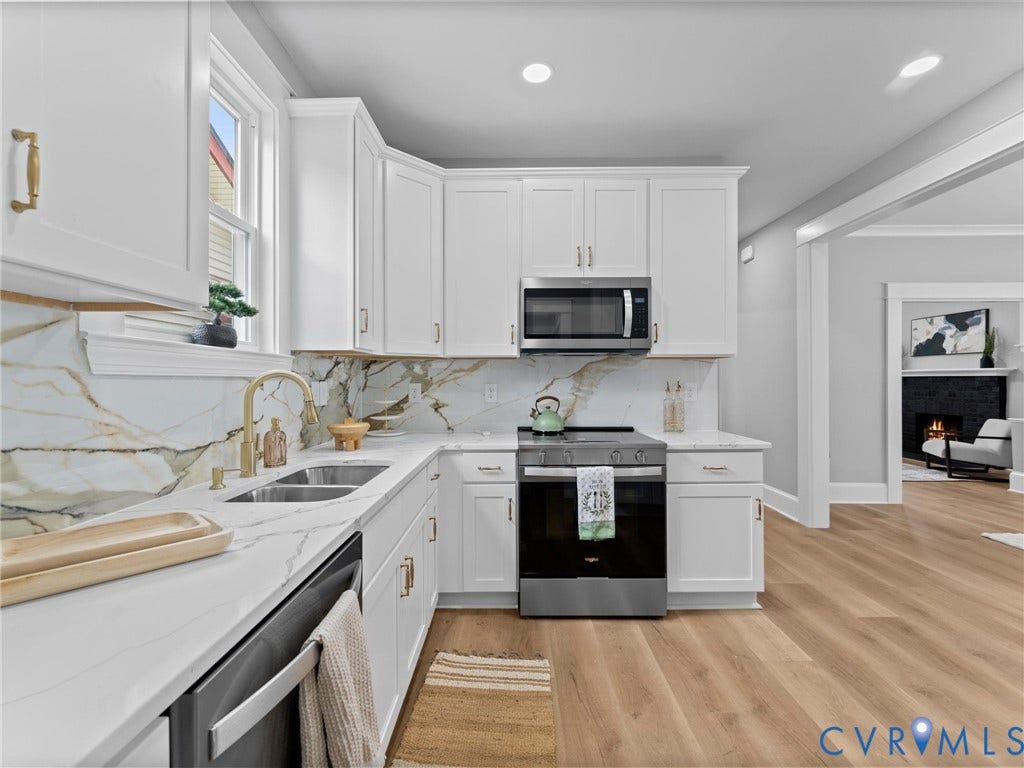 2623 Northumberland Avenue, Richmond, VA 23220 White shaker cabinetry, stone slab backsplash, stainless steel appliances, undermount double basin sink, and wood-finish flooring