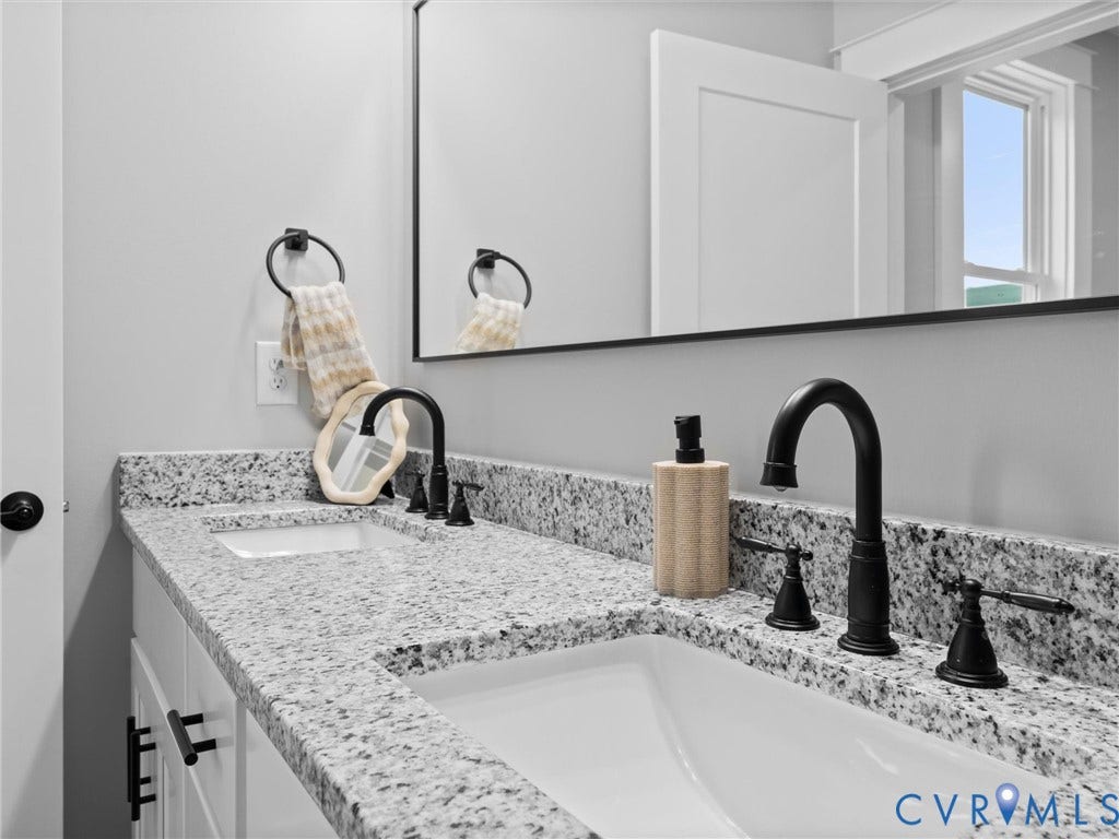 2623 Northumberland Avenue, Richmond, VA 23220 Dual undermount sinks, speckled countertop, matte black fixtures, white shaker cabinetry, and a large wall-mounted mirror