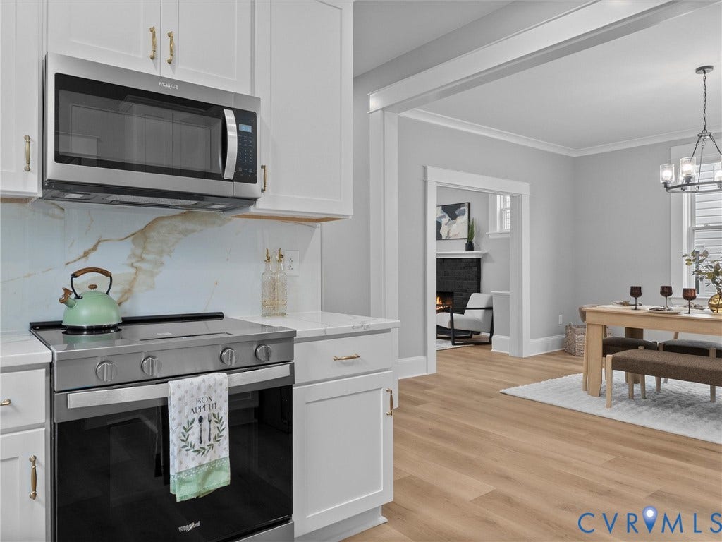 2623 Northumberland Avenue, Richmond, VA 23220 White cabinetry with gold-tone hardware, stainless steel range and microwave, white countertop, patterned backsplash, and wood-finish flooring
