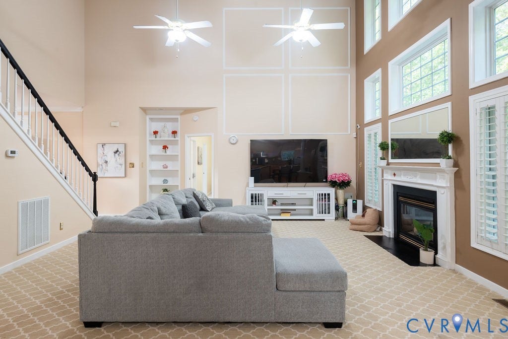 14107 Beachmere Road, Stoney Glen South, Chester, VA 23831 Two-story living room featuring a white staircase with dark handrail, built-in shelving, and a white fireplace with a dark surround