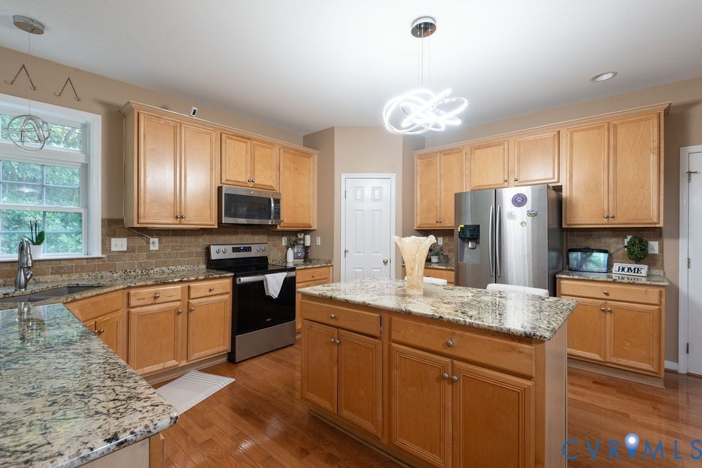 14107 Beachmere Road, Stoney Glen South, Chester, VA 23831 Kitchen featuring wood-finish flooring, granite countertops, light wood cabinetry, stainless steel appliances, and a central island