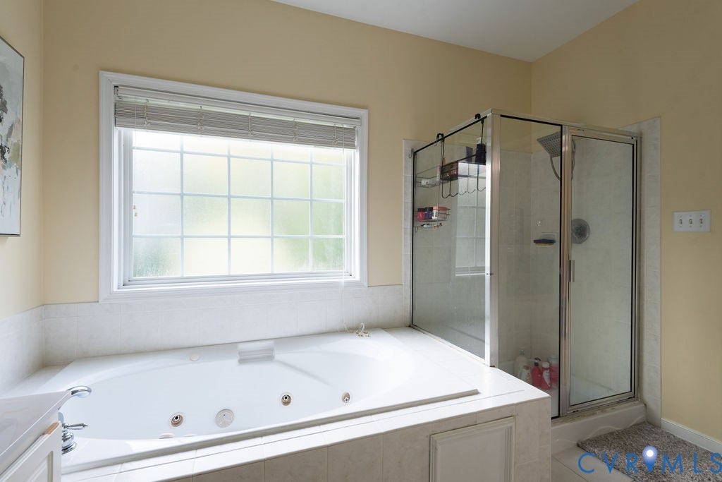 14107 Beachmere Road, Stoney Glen South, Chester, VA 23831 Jetted soaking tub with a tiled surround, frosted window with white blinds, and a glass-enclosed shower