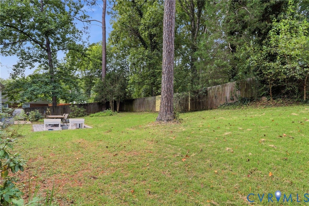 1427 Spring Grove Drive, Richmond, VA 23225 Fenced backyard with mature trees, green lawn, and a paved patio area