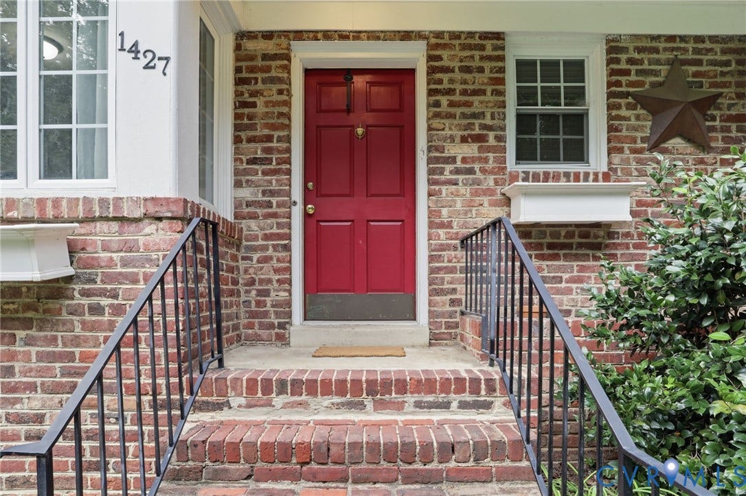 1427 Spring Grove Drive, Richmond, VA 23225 Brick exterior with a red paneled entry door, white window boxes, and black wrought iron railings