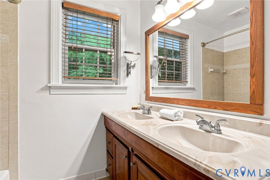 1427 Spring Grove Drive, Richmond, VA 23225 Dual vanity with an integrated countertop, wood-finish cabinetry, and chrome fixtures