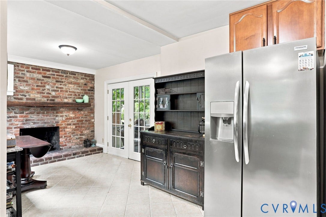 1427 Spring Grove Drive, Richmond, VA 23225 Exposed brick fireplace with a wood-finish mantel, white French doors, and light-toned tile flooring