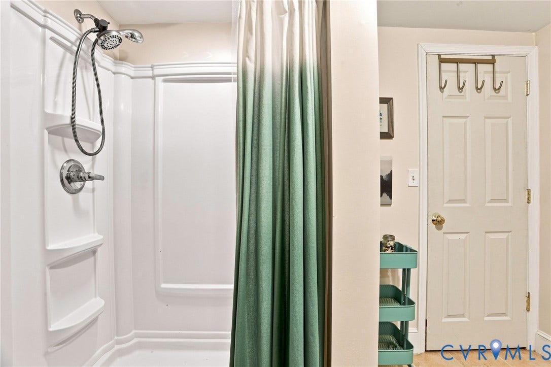 1427 Spring Grove Drive, Richmond, VA 23225 White shower surround with built-in shelving and a handheld showerhead