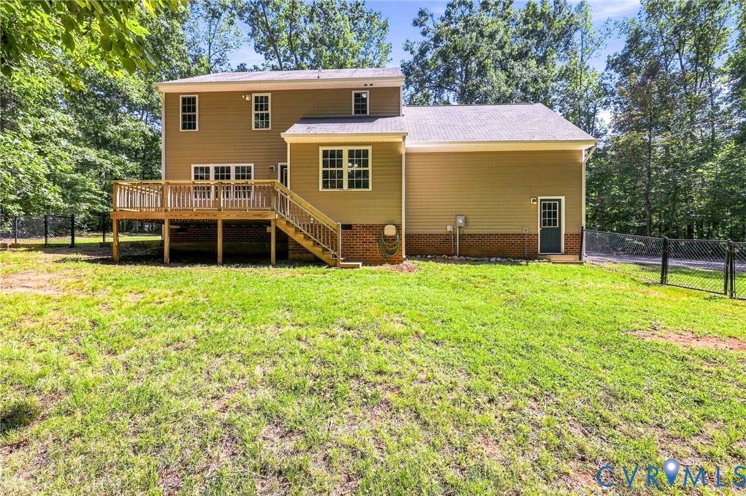 3522 Fairfield Road, Powhatan, VA 23139 Expansive backyard with a wooden deck, chain link fencing, and a brick foundation