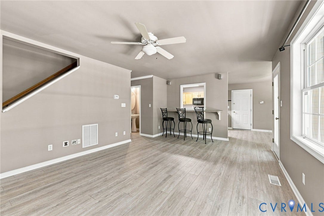 3522 Fairfield Road, Powhatan, VA 23139 Wood-finish flooring, neutral wall tones, white ceiling fan, staircase with wood handrail, and a pass-through window with a breakfast bar