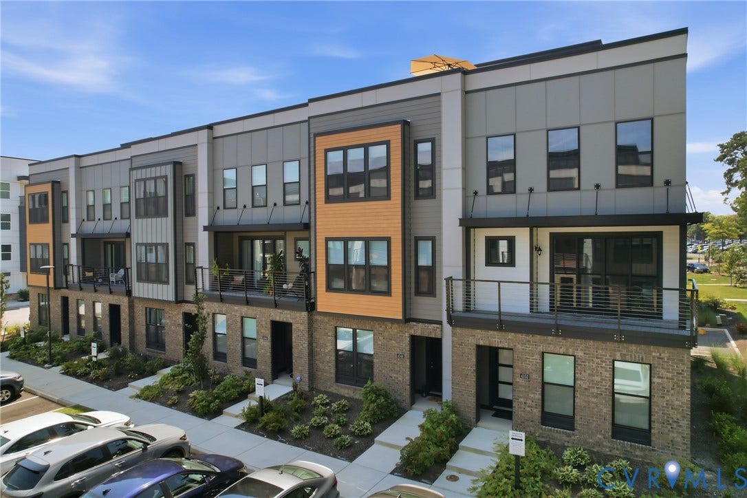 Modern multi-story facade featuring brick, horizontal siding, and wood-look accents