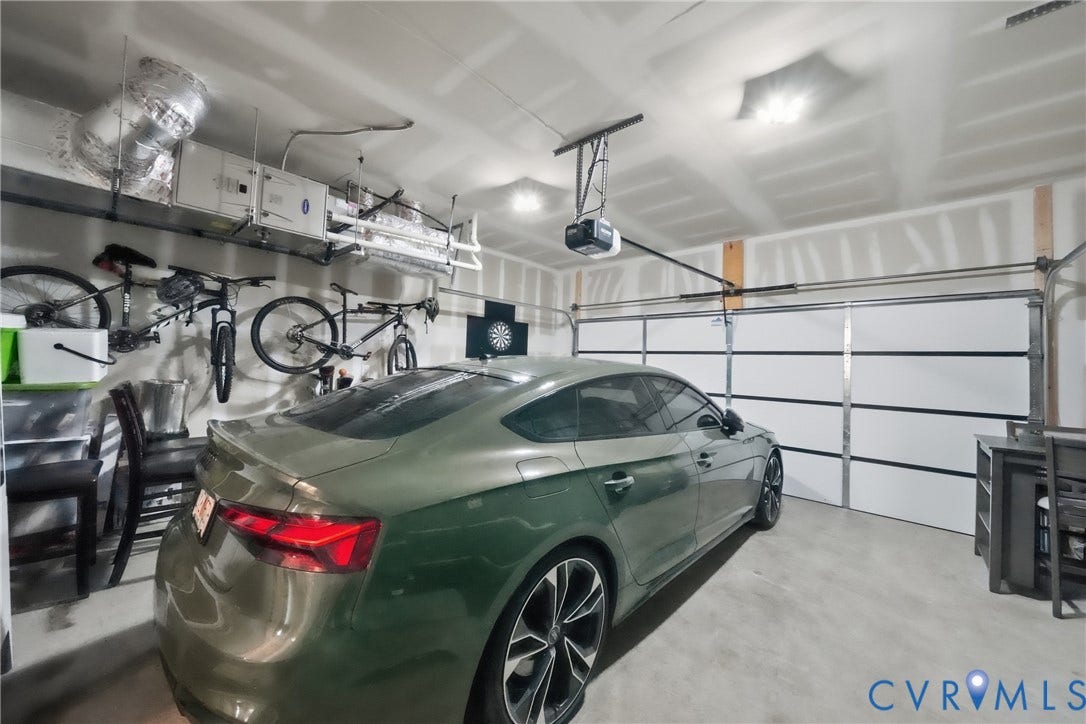 Attached two-car garage with a white sectional garage door and exposed overhead garage door opener