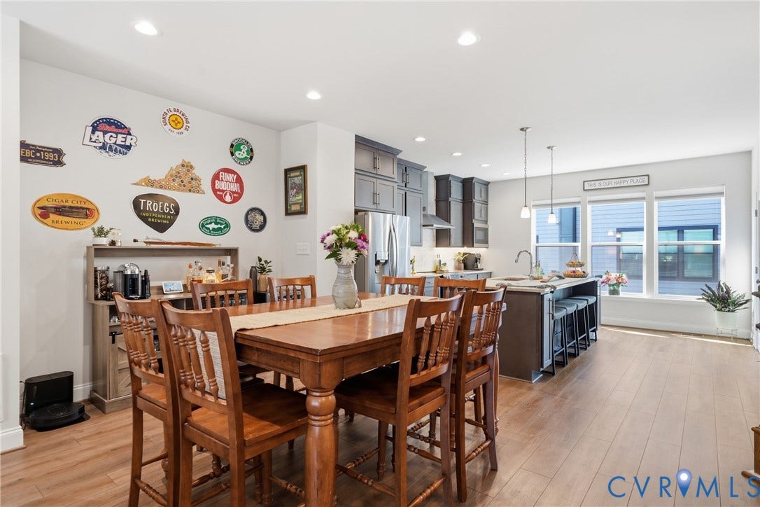 Open-concept living area with wood-finish flooring, recessed lighting, and a kitchen island with seating