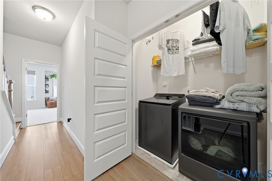 Laundry closet with built-in shelving, white paneled door, and wood-finish flooring