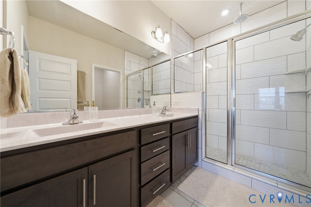 Dual vanity with undermount sinks, stone-finish countertop, and dark wood-finish cabinetry