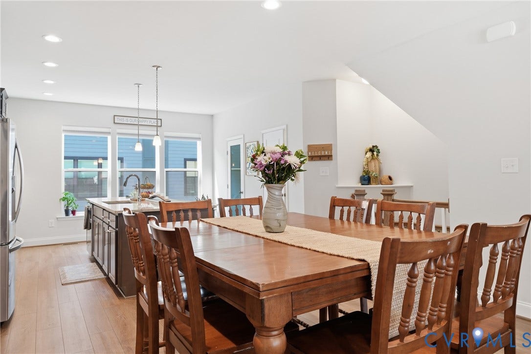 Recessed ceiling lighting, wood-finish flooring, contemporary kitchen island with pendant lighting, stainless steel refrigerator, and built-in shelving