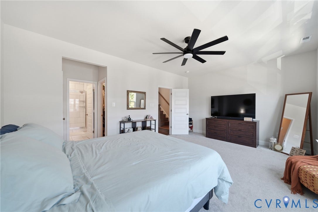 Carpeted flooring, contemporary ceiling fan, white walls, and a walk-in shower with tile surround