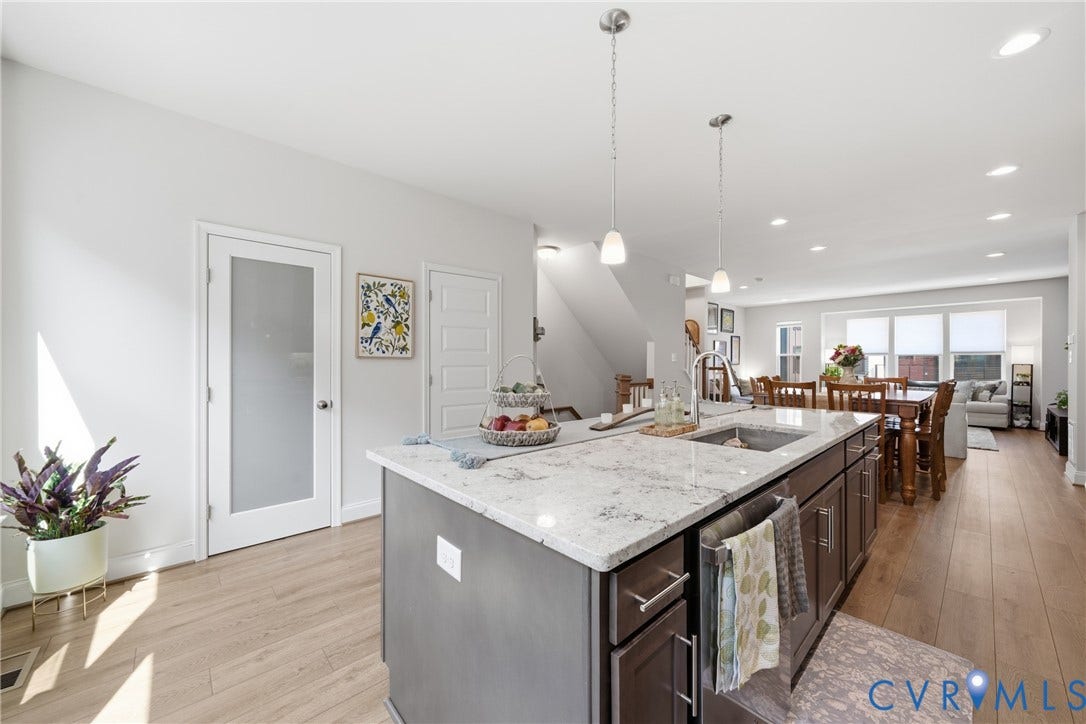 Kitchen island featuring a stainless steel sink with a high-arch faucet, granite-style countertop, and dark wood-finish cabinetry with silver hardware