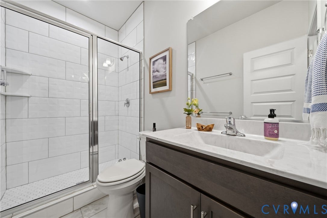 Walk-in shower with clear glass enclosure and subway tile surround