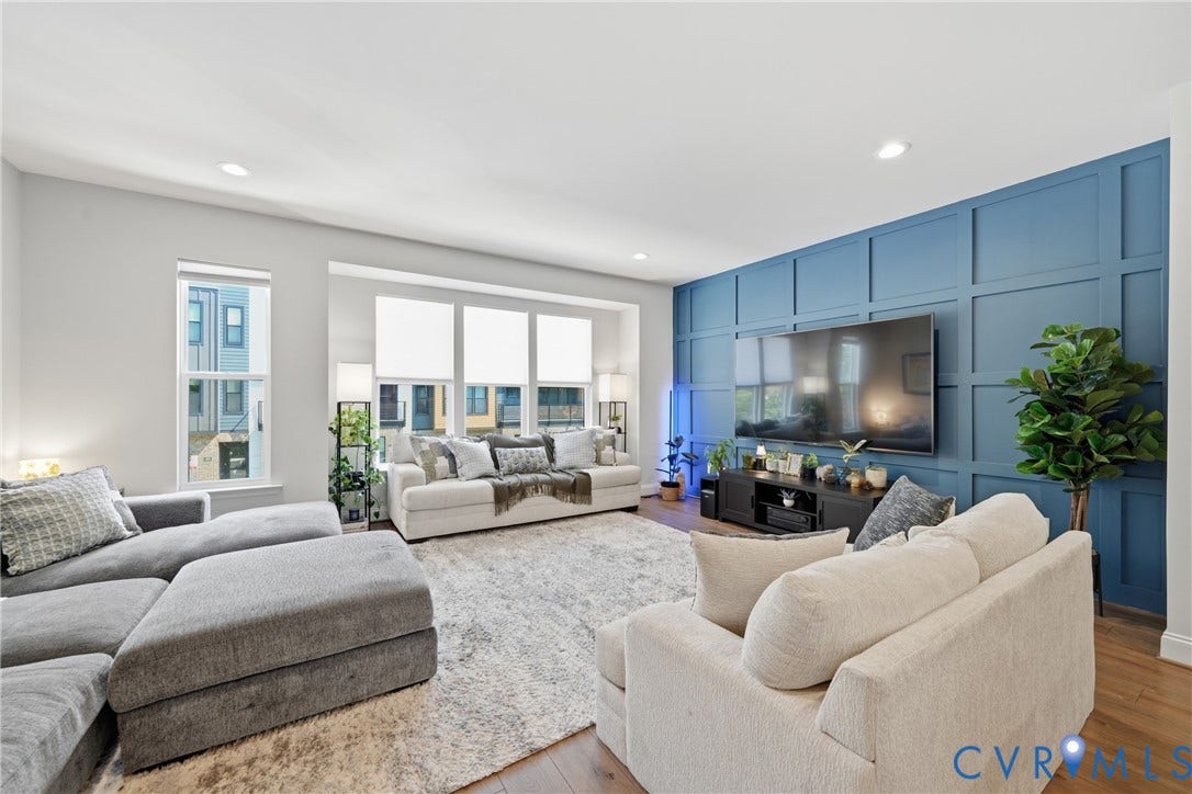 Open-concept living space featuring wood-finish flooring, recessed lighting, expansive windows, and an accent wall with wainscoting