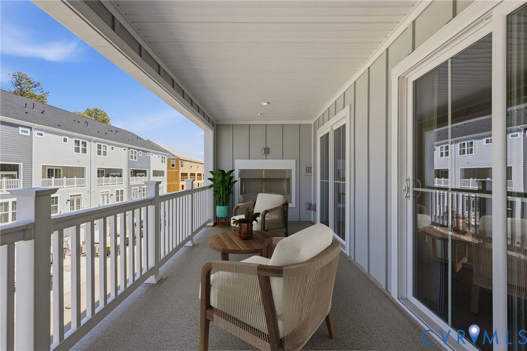 Spacious covered balcony featuring a built-in fireplace, two sets of glass sliding doors, and white railing