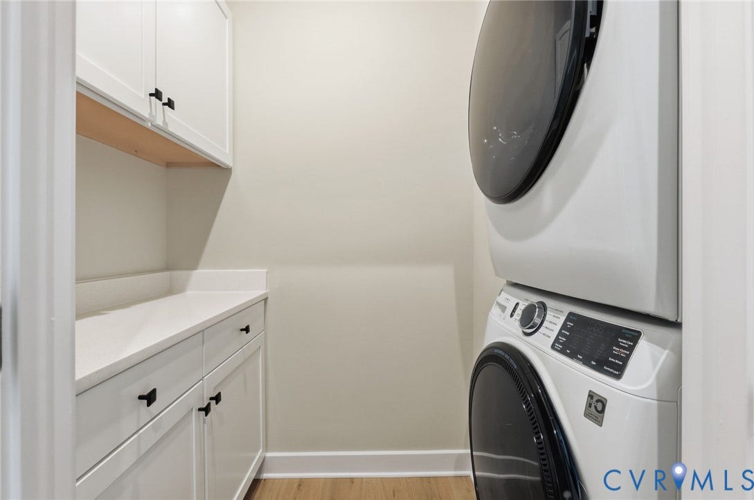 White cabinetry with black hardware, white countertop, and wood-finish flooring