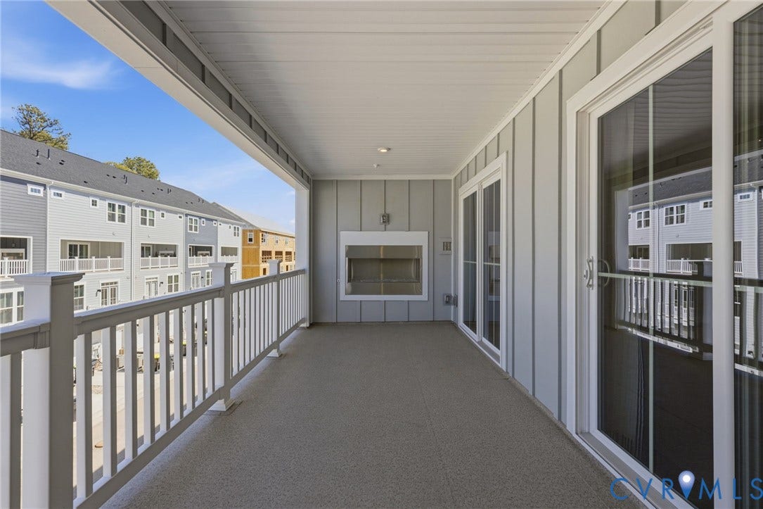 Covered balcony featuring a built-in outdoor fireplace, a textured flooring surface, and white railing