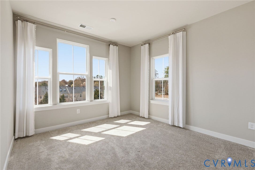 Neutral wall paint, plush carpeting, multiple windows, white window trim, and white baseboards