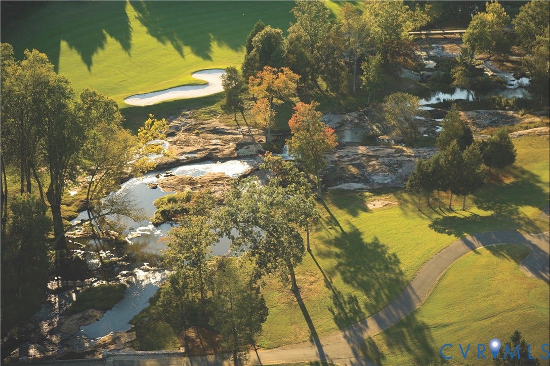 2025 Wilkhaven Terrace, Powhatan, VA 23139 Manicured golf course featuring a sand trap, mature trees, natural rock formations, a flowing stream, and a paved pathway