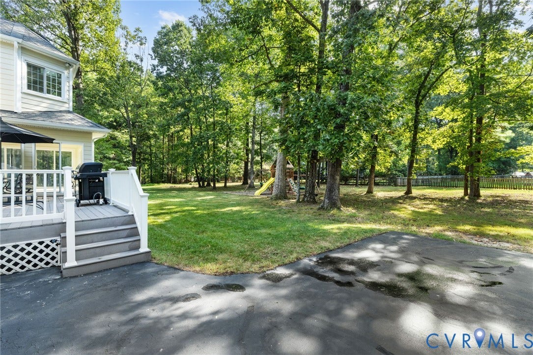 14411 Galloway Court, Salisbury, Midlothian, VA 23113 Expansive lawn bordered by mature trees and a wood fence, with a multi-level deck featuring white railings and steps