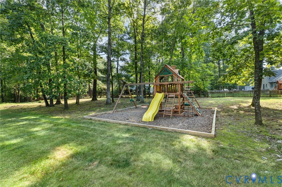 14411 Galloway Court, Salisbury, Midlothian, VA 23113 Expansive backyard with a wooden playset featuring a yellow slide, swings, and natural wood chip ground cover