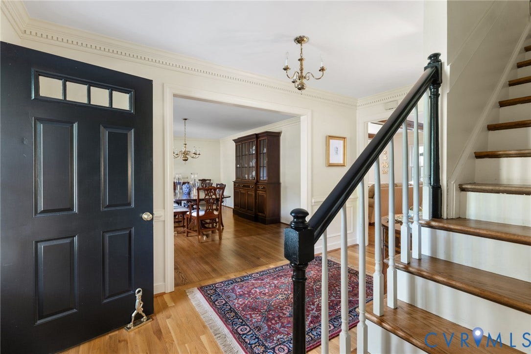 14411 Galloway Court, Salisbury, Midlothian, VA 23113 Black paneled entry door with transom windows, hardwood flooring, detailed crown molding, staircase with wood treads and balusters, and a brass chandelier