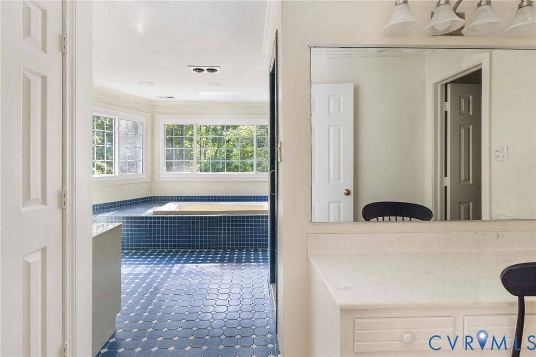 14411 Galloway Court, Salisbury, Midlothian, VA 23113 Built-in soaking tub with blue mosaic tile surround, multiple windows with grid patterns, recessed lighting, and a vanity with a built-in dressing table
