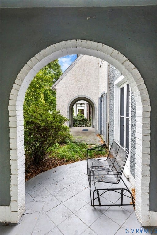 2415 Maplewood Avenue, Byrd Park, Richmond, VA 23220 Arched brick entryway with a painted finish, leading to an exterior corridor featuring a patterned concrete patio
