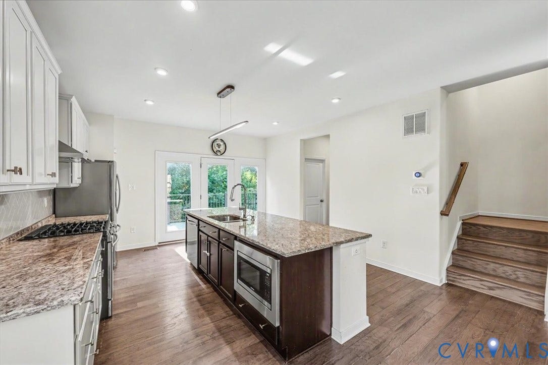 1141 Broad Hill Trace, Saunders Station Townes, Henrico, VA 23233 Well-appointed kitchen featuring granite countertops, stainless steel appliances, white cabinetry, a central island with a built-in microwave, and wood-finish flooring