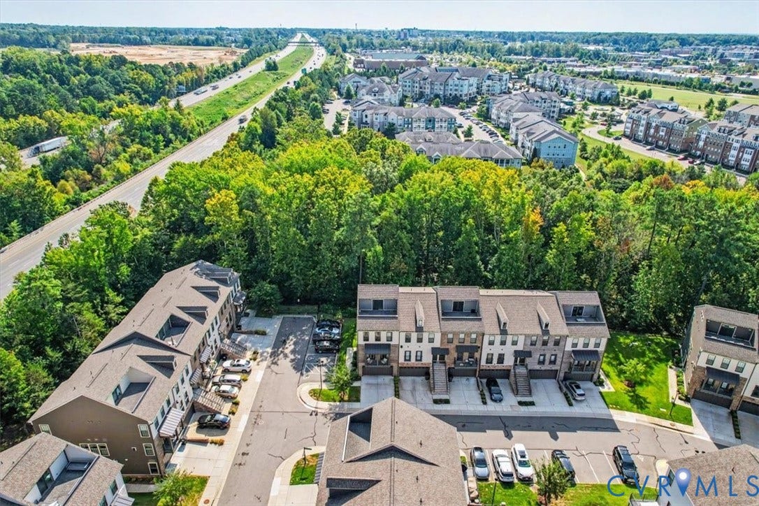 1141 Broad Hill Trace, Saunders Station Townes, Henrico, VA 23233 Modern townhome development with private parking spaces, surrounded by mature trees, and a nearby multi-lane roadway