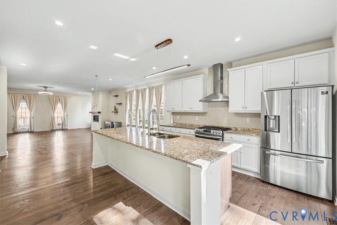 1141 Broad Hill Trace, Saunders Station Townes, Henrico, VA 23233 Open-concept kitchen featuring an island with a sink, white cabinetry, stainless steel appliances, and wood-finish flooring