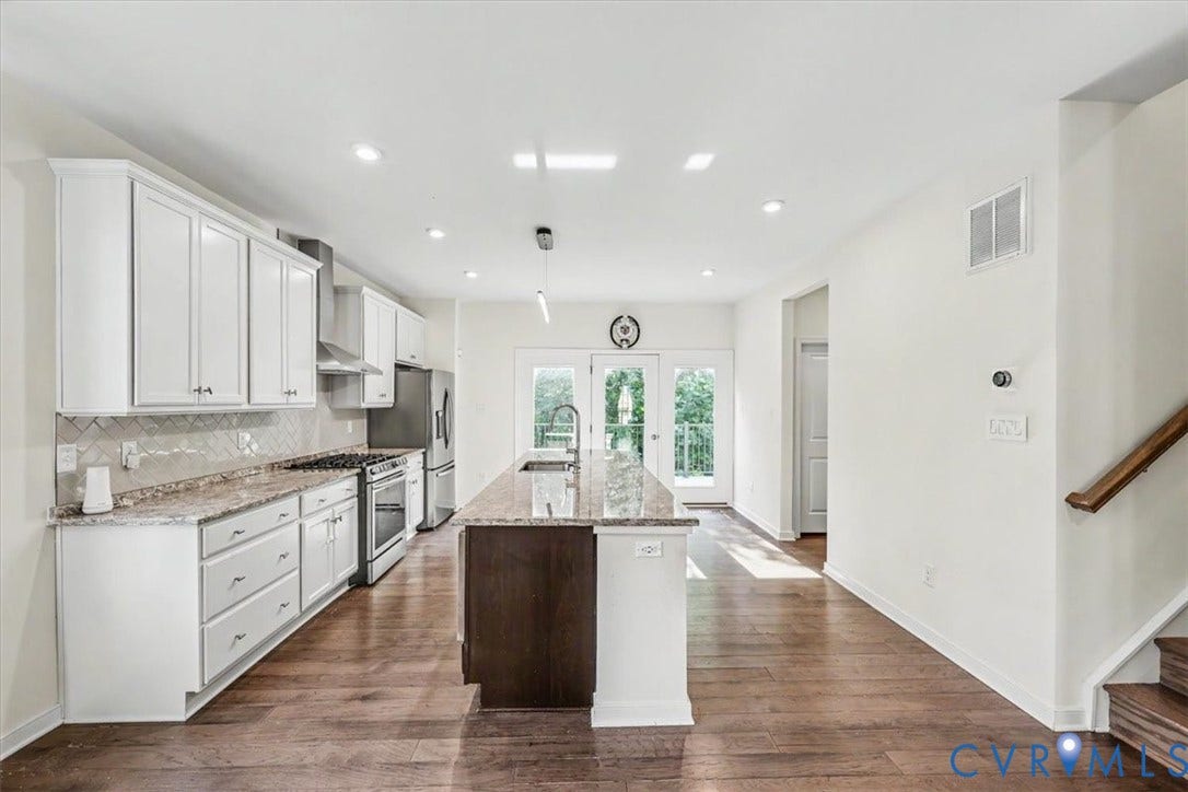 1141 Broad Hill Trace, Saunders Station Townes, Henrico, VA 23233 Open-concept kitchen featuring white cabinetry, stainless steel appliances, a center island with granite countertops, and wood-finish flooring