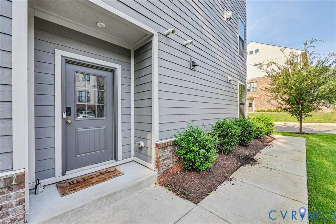 1141 Broad Hill Trace, Saunders Station Townes, Henrico, VA 23233 Entryway featuring gray siding, a paneled door with glass inserts, recessed lighting, and a concrete pathway with landscaping