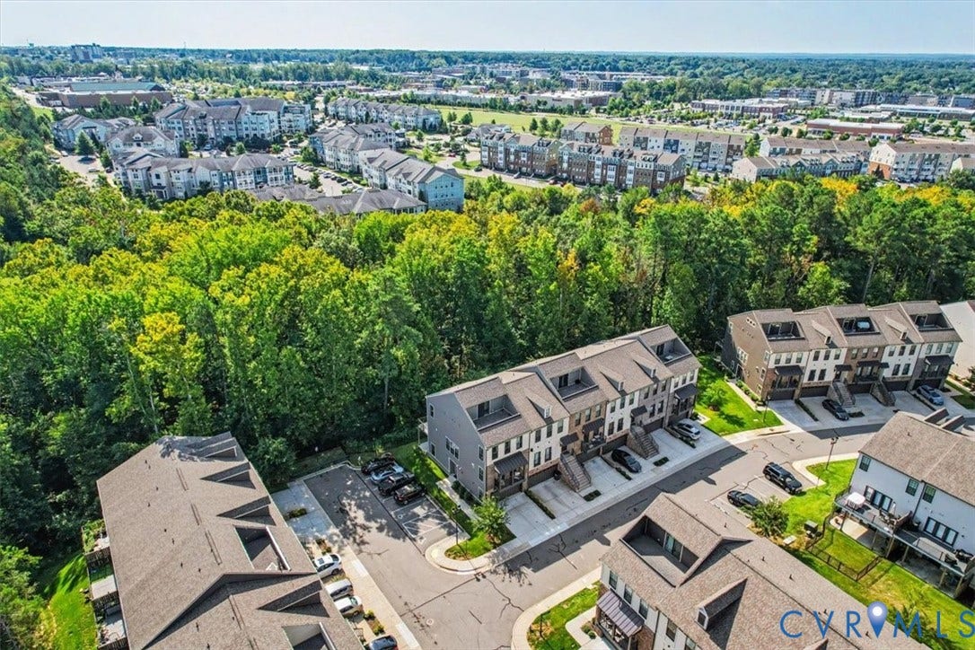 1141 Broad Hill Trace, Saunders Station Townes, Henrico, VA 23233 Aerial perspective showcasing a residential community with townhomes and apartment buildings, bordered by mature trees