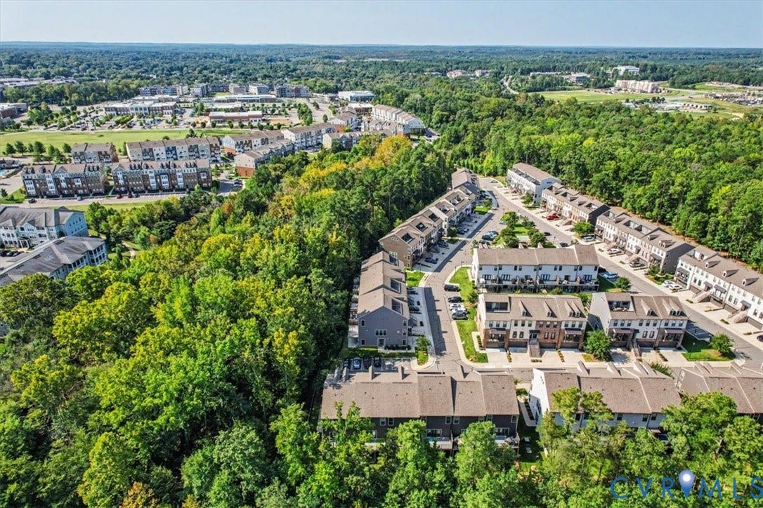 1141 Broad Hill Trace, Saunders Station Townes, Henrico, VA 23233 Residential development with multiple townhome-style buildings, surrounded by extensive natural tree cover, and paved roadways with designated parking spaces