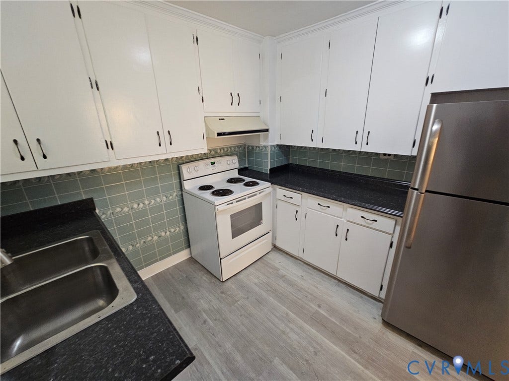 White cabinetry, stainless steel refrigerator, white range, dark countertops, and wood-finish flooring