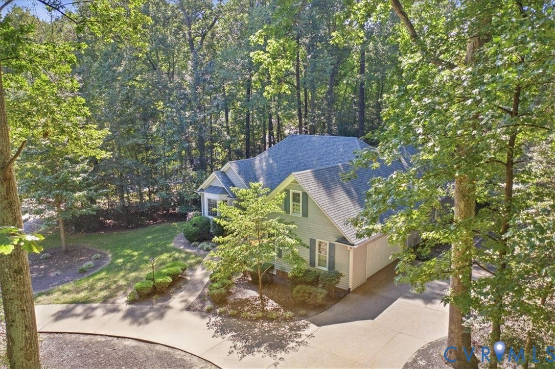 Light gray siding exterior with a dark gray shingle roof, surrounded by mature trees