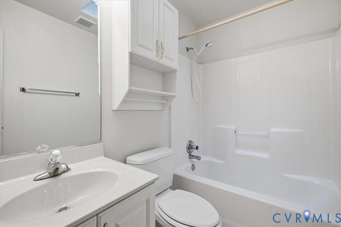 White bathroom featuring a vanity with an integrated sink, built-in medicine cabinet, and a shower-tub combination
