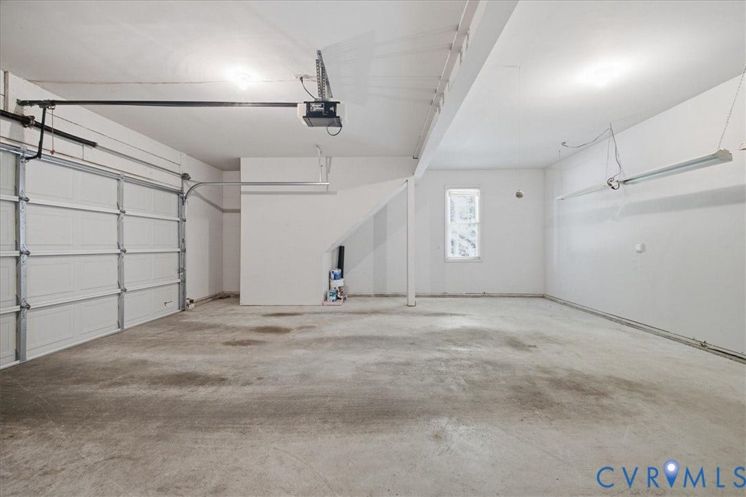 Attached garage with a panel garage door, concrete flooring, overhead lighting, and a single window
