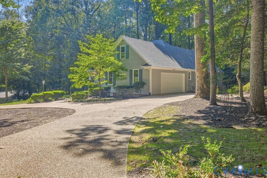 Gable-roofed home with siding exterior, attached garage, and a gravel driveway