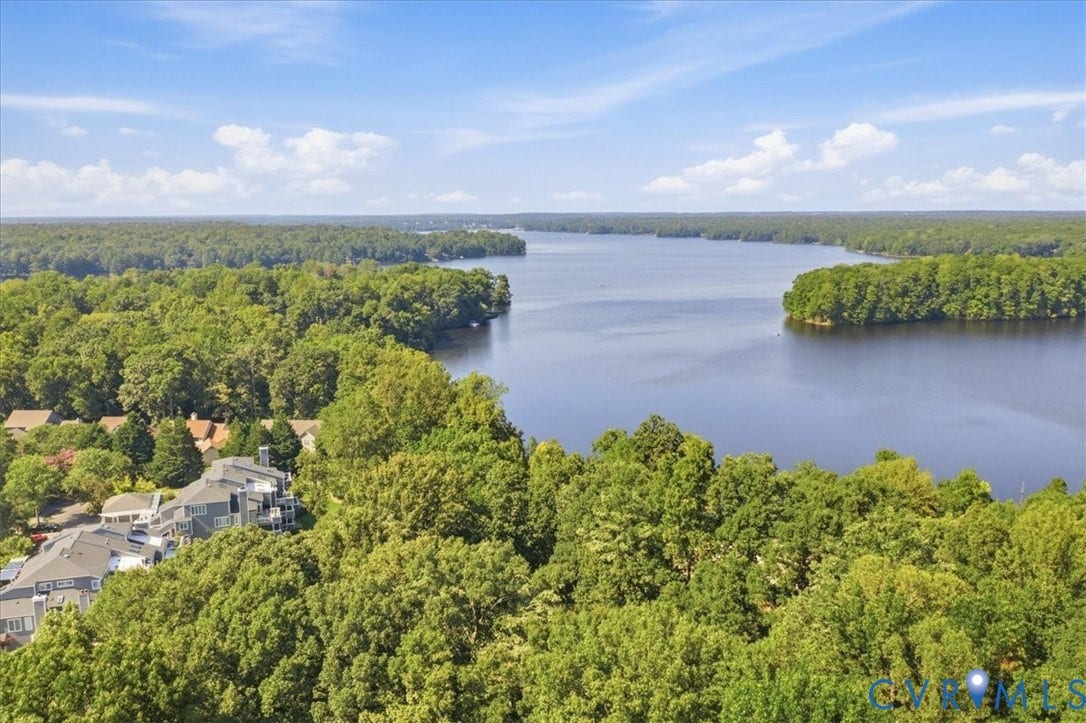 Expansive body of water bordered by dense tree coverage and surrounding residential structures