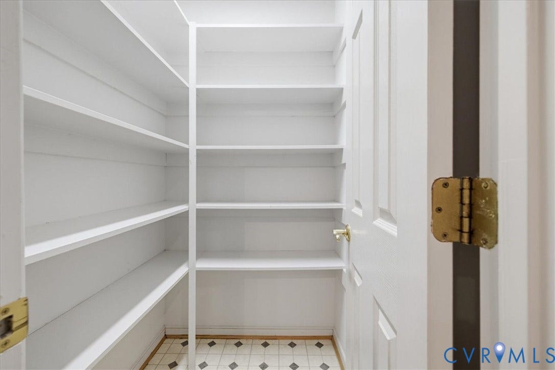 Built-in shelving with multiple shelves, white painted walls, and patterned tile flooring