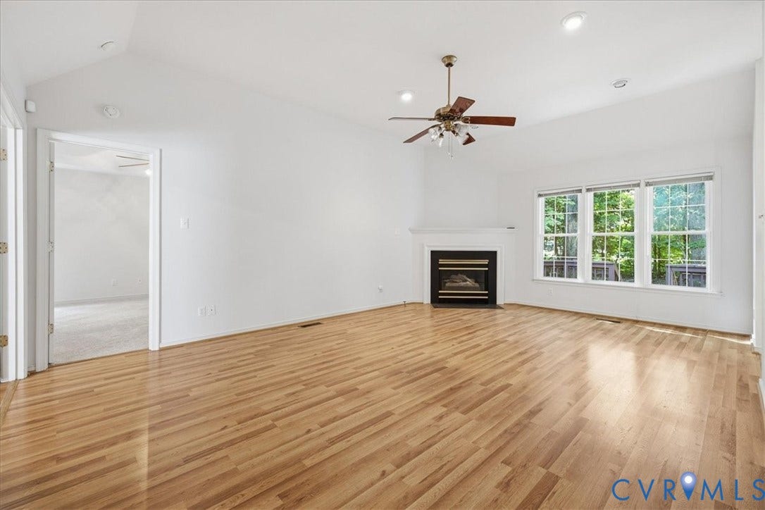 Hardwood flooring, vaulted ceiling, built-in fireplace, ceiling fan, and large windows